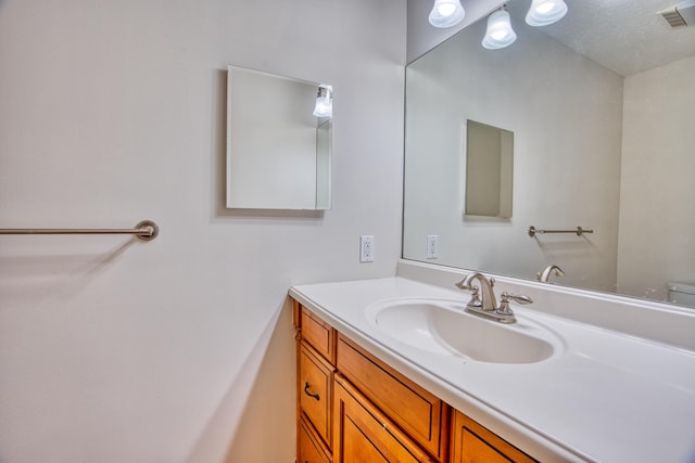 bathroom with vanity, visible vents, and a textured ceiling