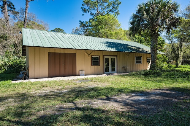 back of property with a yard, french doors, and metal roof