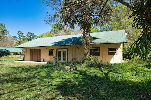 back of house with a yard, french doors, board and batten siding, and metal roof