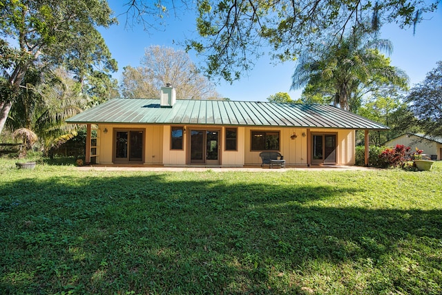 back of house with a patio area, a lawn, metal roof, and a standing seam roof