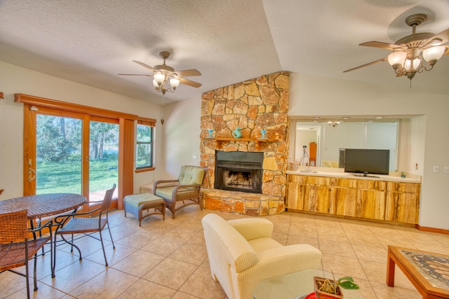 living room with ceiling fan, lofted ceiling, light tile patterned flooring, and a fireplace