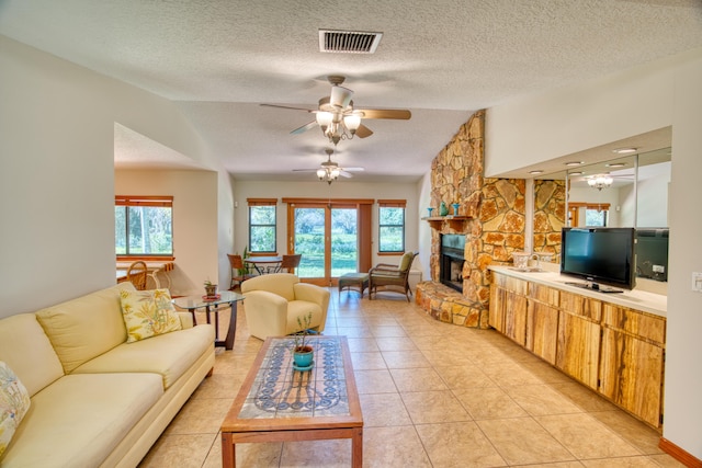 living area with visible vents, a ceiling fan, a textured ceiling, a fireplace, and light tile patterned floors