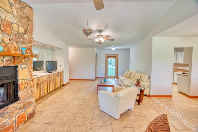 living area featuring a stone fireplace, light tile patterned floors, a ceiling fan, and a textured ceiling