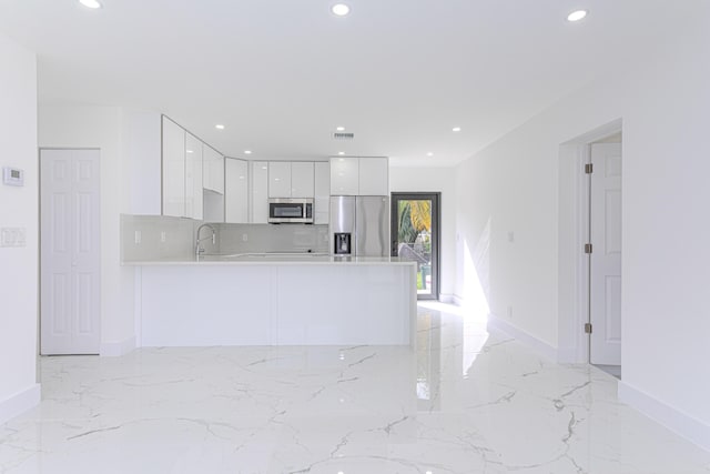 kitchen featuring sink, tasteful backsplash, appliances with stainless steel finishes, kitchen peninsula, and white cabinets