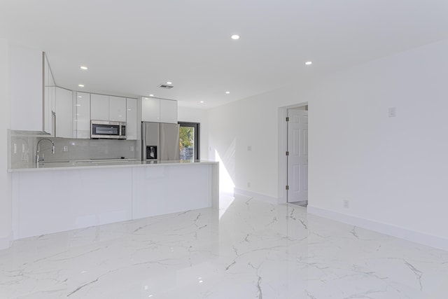 kitchen with tasteful backsplash, white cabinetry, appliances with stainless steel finishes, and kitchen peninsula