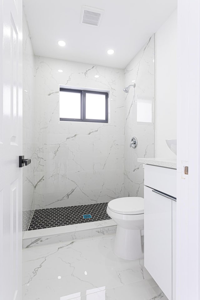 bathroom with vanity, toilet, and a tile shower