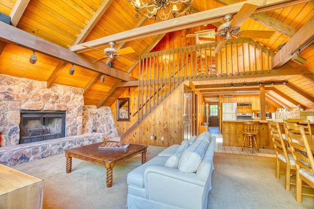 carpeted living room featuring stairway, wooden walls, lofted ceiling with beams, a fireplace, and wood ceiling