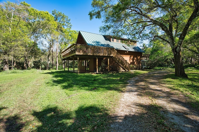 view of front of property with a wooden deck, a standing seam roof, stairs, a front lawn, and metal roof