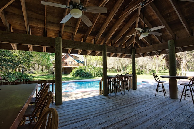 deck featuring a gazebo, a ceiling fan, an outdoor pool, and outdoor dry bar