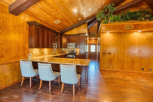 kitchen featuring glass insert cabinets, appliances with stainless steel finishes, dark wood-type flooring, and light stone countertops