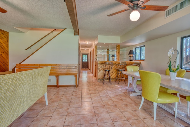 tiled dining room with visible vents, beam ceiling, a textured ceiling, and a ceiling fan