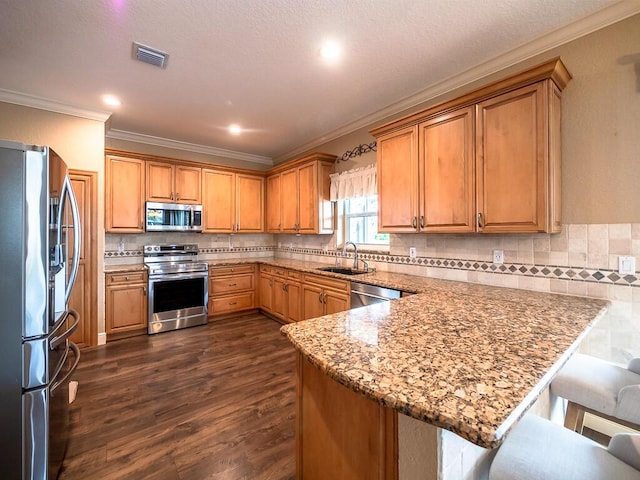 kitchen with appliances with stainless steel finishes, sink, a kitchen breakfast bar, light stone counters, and kitchen peninsula