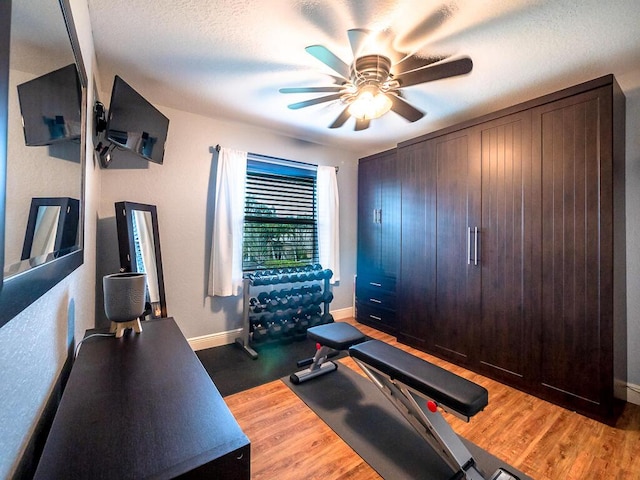 workout area featuring ceiling fan, wood-type flooring, and a textured ceiling