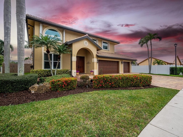 mediterranean / spanish-style home featuring a garage and a lawn