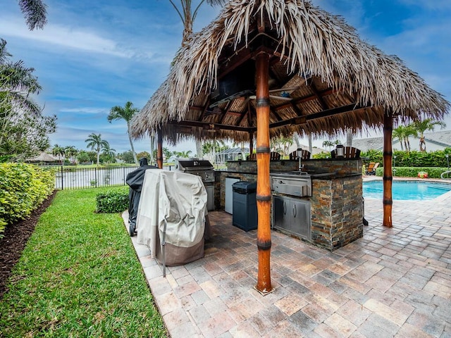 view of patio / terrace with a fenced in pool, a gazebo, grilling area, and an outdoor kitchen