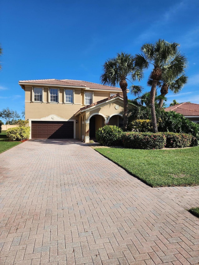 mediterranean / spanish home featuring a garage and a front lawn