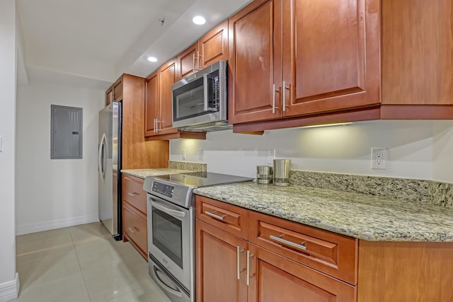 kitchen with light tile patterned flooring, appliances with stainless steel finishes, electric panel, and light stone countertops