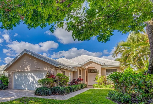 ranch-style house featuring a garage and a front lawn