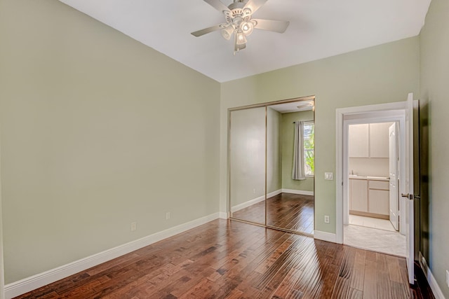 unfurnished bedroom featuring ensuite bath, wood-type flooring, a closet, and ceiling fan