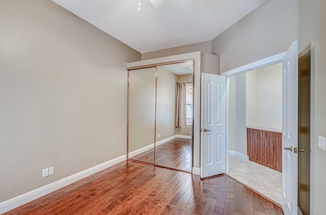 unfurnished bedroom with hardwood / wood-style flooring, ceiling fan, and a closet