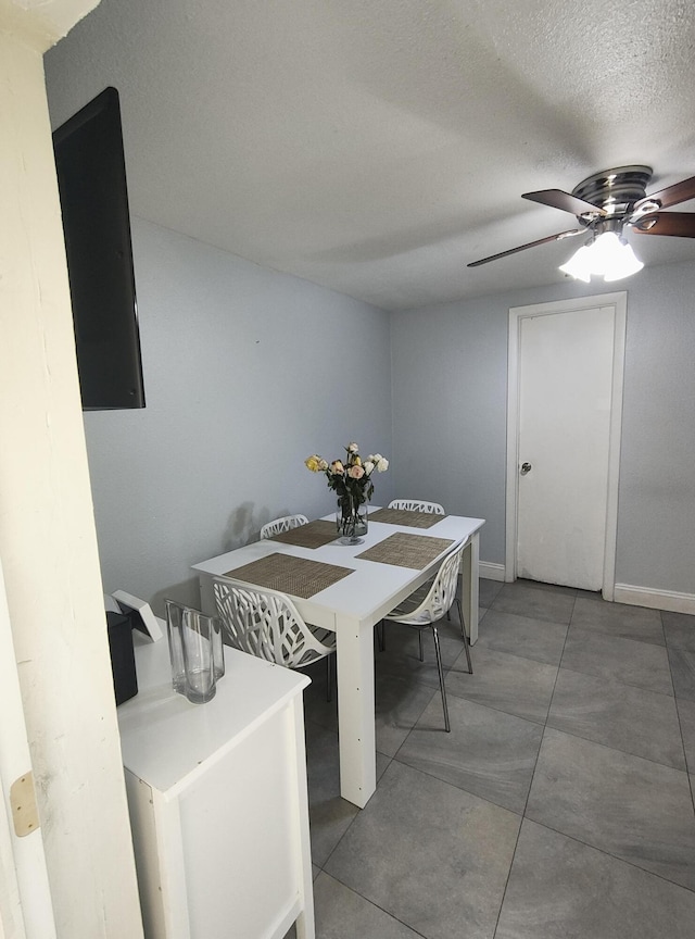 tiled dining room with ceiling fan and a textured ceiling