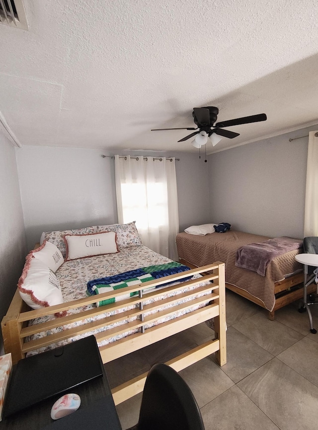 bedroom with a textured ceiling, tile patterned floors, and ceiling fan