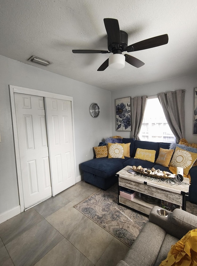 living room featuring ceiling fan and a textured ceiling