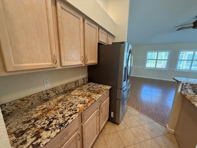 kitchen with stainless steel refrigerator with ice dispenser, light tile patterned floors, open floor plan, light brown cabinets, and ceiling fan