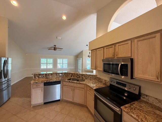 kitchen featuring light tile patterned floors, appliances with stainless steel finishes, vaulted ceiling, a sink, and a peninsula