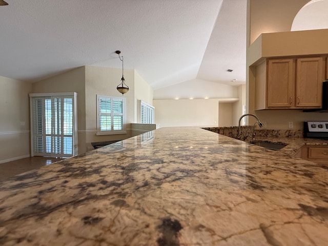 kitchen featuring brown cabinets, light stone countertops, vaulted ceiling, pendant lighting, and a sink