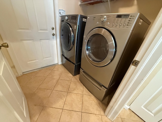 washroom featuring laundry area, independent washer and dryer, and light tile patterned floors