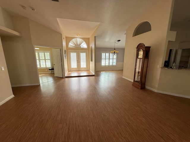 interior space with french doors, an inviting chandelier, dark wood-type flooring, high vaulted ceiling, and baseboards