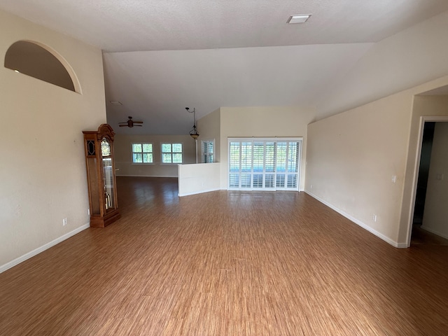 unfurnished living room featuring lofted ceiling, visible vents, baseboards, and wood finished floors