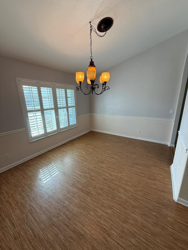 unfurnished room with a notable chandelier and baseboards