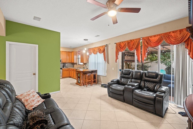 tiled living room featuring a healthy amount of sunlight, a textured ceiling, and ceiling fan