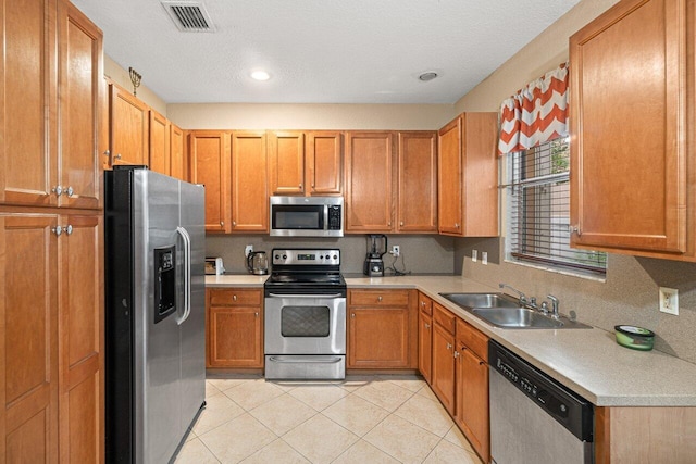 kitchen featuring stainless steel appliances, sink, and light tile patterned floors