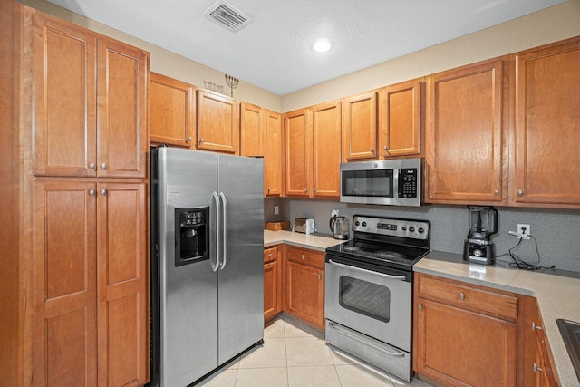 kitchen featuring light tile patterned flooring, stainless steel appliances, and a textured ceiling