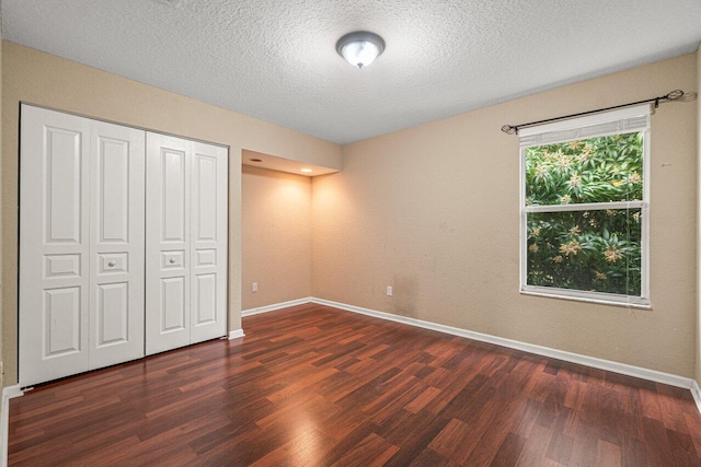 unfurnished bedroom featuring dark wood-type flooring, a closet, and a textured ceiling