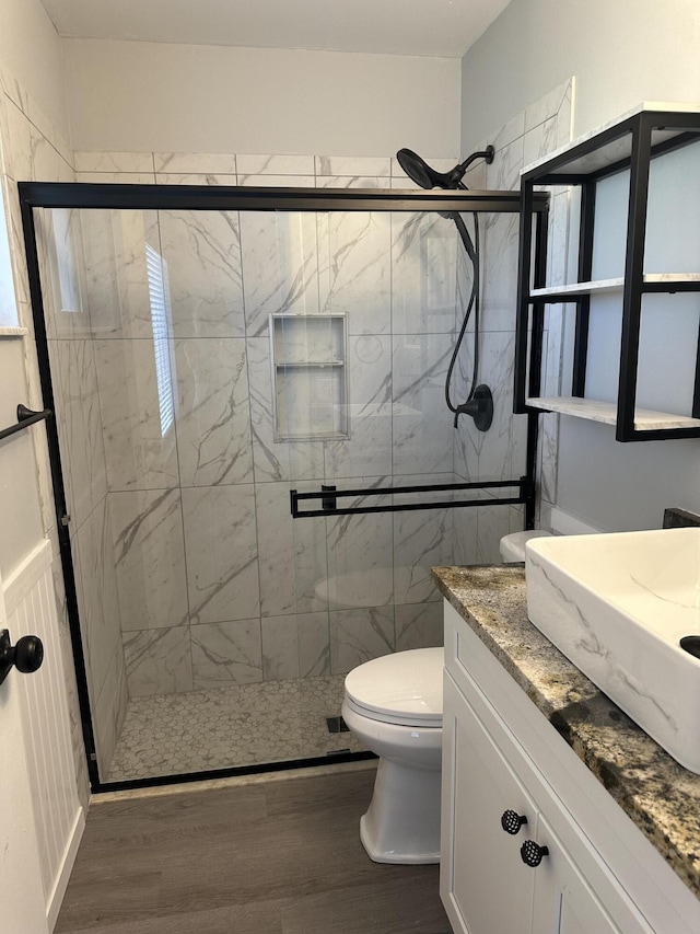 bathroom featuring hardwood / wood-style flooring, vanity, an enclosed shower, and toilet