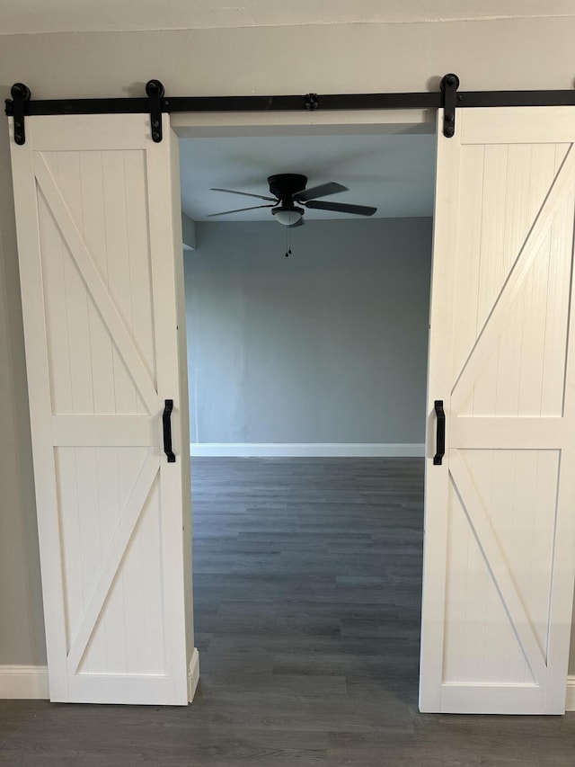 hall with dark wood-type flooring and a barn door