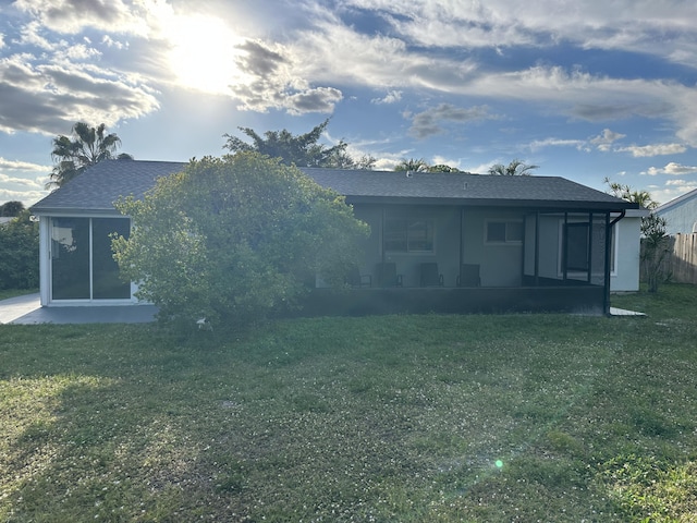 back of property featuring a sunroom and a lawn