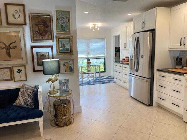 kitchen with light tile patterned floors, recessed lighting, white cabinetry, backsplash, and stainless steel fridge with ice dispenser