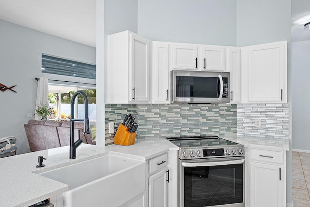 kitchen with light stone counters, sink, white cabinets, and appliances with stainless steel finishes