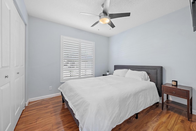 bedroom with dark wood-type flooring, ceiling fan, and a closet