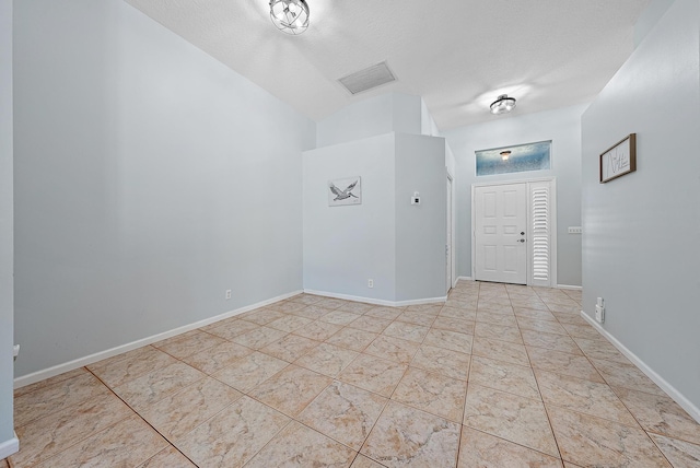 foyer with light tile patterned floors, vaulted ceiling, and a textured ceiling