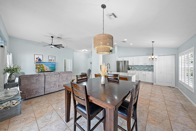 tiled dining space featuring ceiling fan with notable chandelier and vaulted ceiling