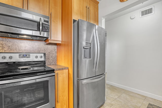 kitchen with tasteful backsplash, stainless steel appliances, and light tile patterned floors