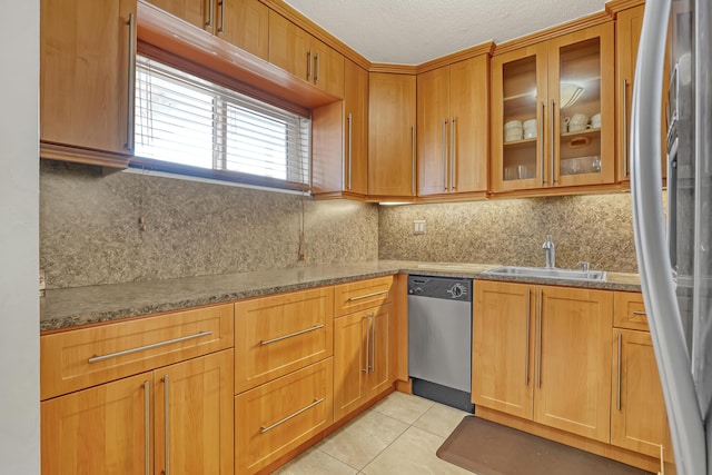 kitchen with sink, light tile patterned floors, stone counters, stainless steel appliances, and tasteful backsplash