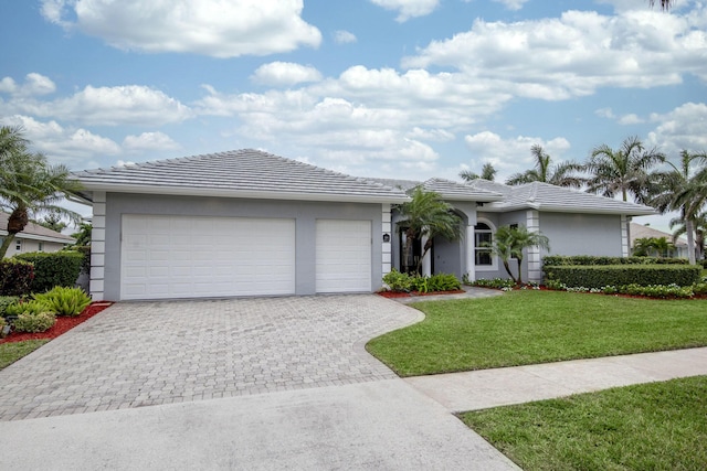 view of front of property featuring decorative driveway, a tile roof, a front yard, and stucco siding