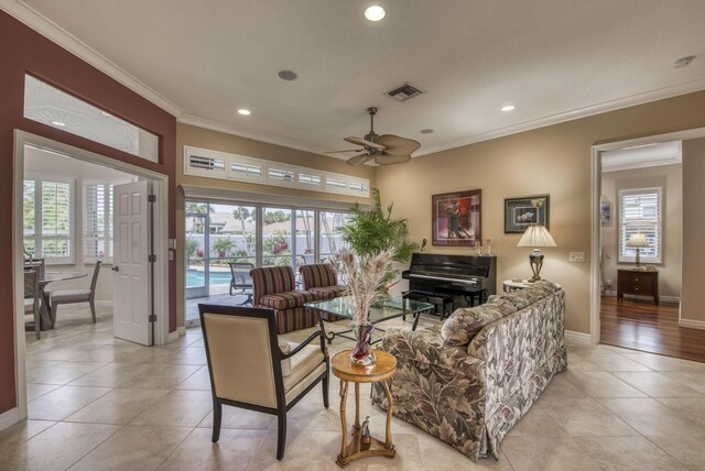 tiled living room featuring ceiling fan and ornamental molding